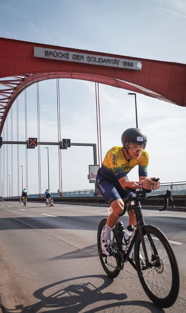 Gert-Jan Helmink in professioneel wieler tenue op een tijdritfiets over de Brücke der Solidarität tijdens een wedstrijd.
